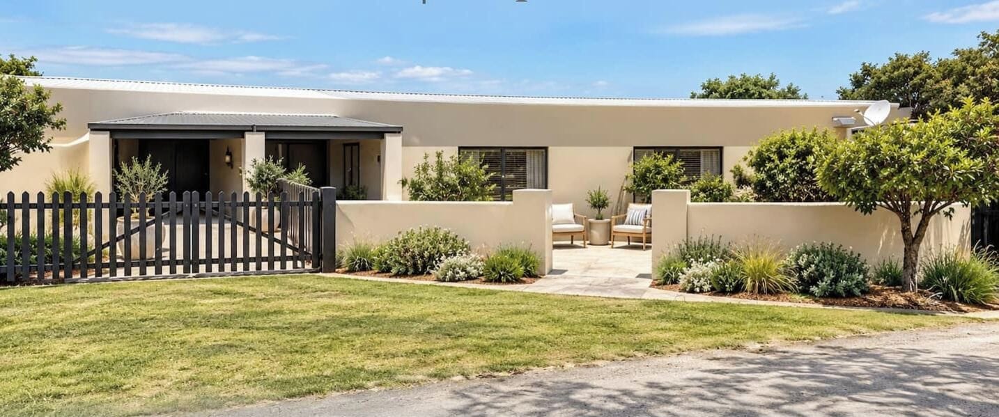 Una casa moderna con entrada pavimentada, patio delantero cercado y antena parabólica.