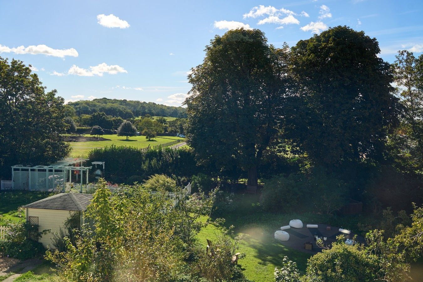 A residential property with a garden, a white fence, and a large tree.