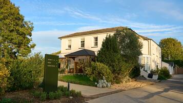 A two-story building with a sign indicating rooms 1-16 and a direction to Sussex House.
