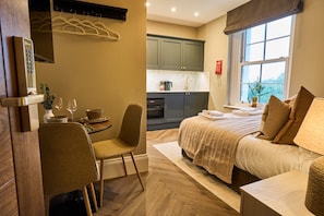 A hotel room with a bed, a dining area with a table and chairs, a kitchen area, and a window with a view. - *NEW* Castle & Countryside Views, Close To Goodwood (Warningcamp)
