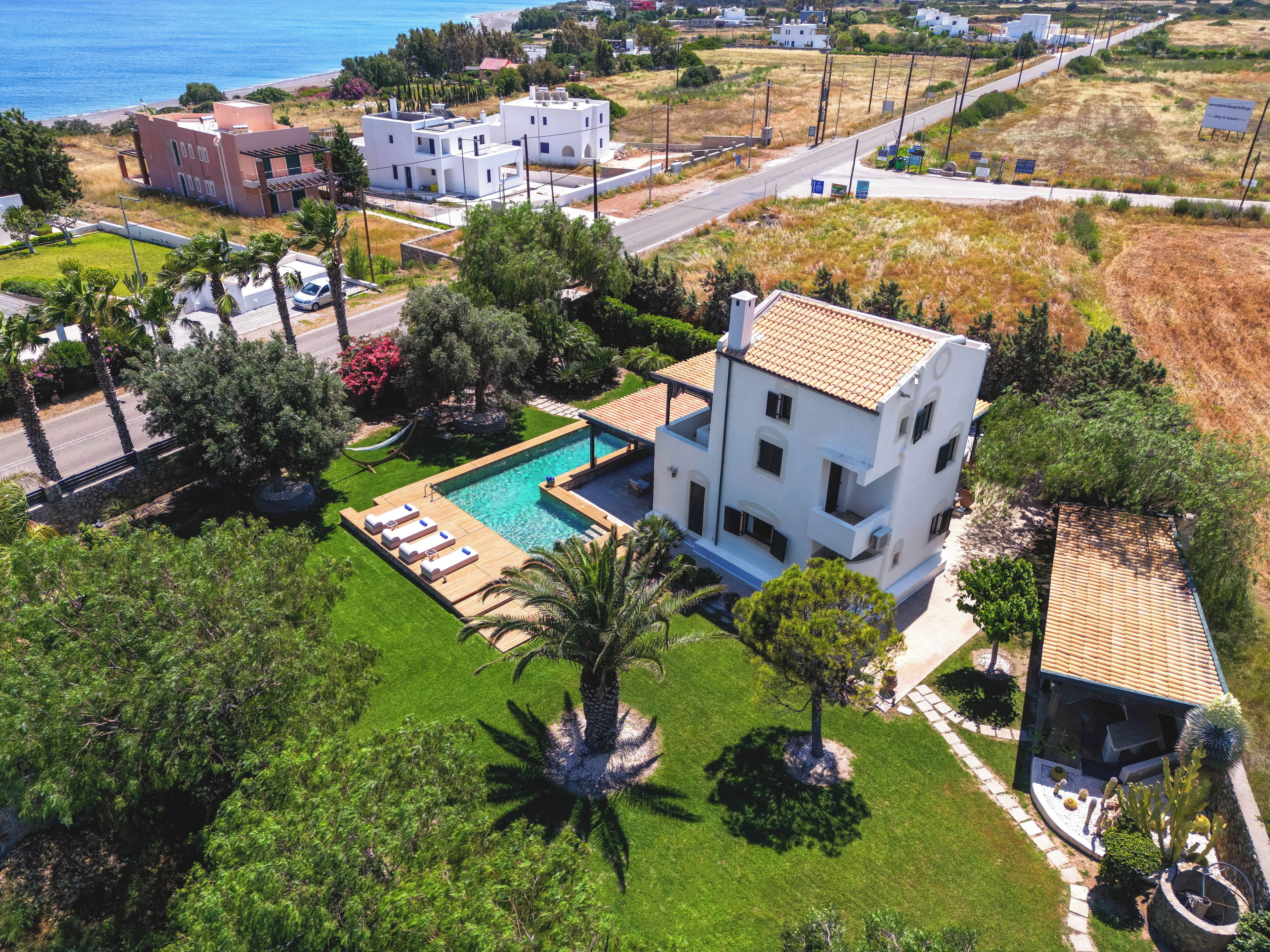 Zona residencial con una casa grande que tiene piscina, varios balcones y jardín.