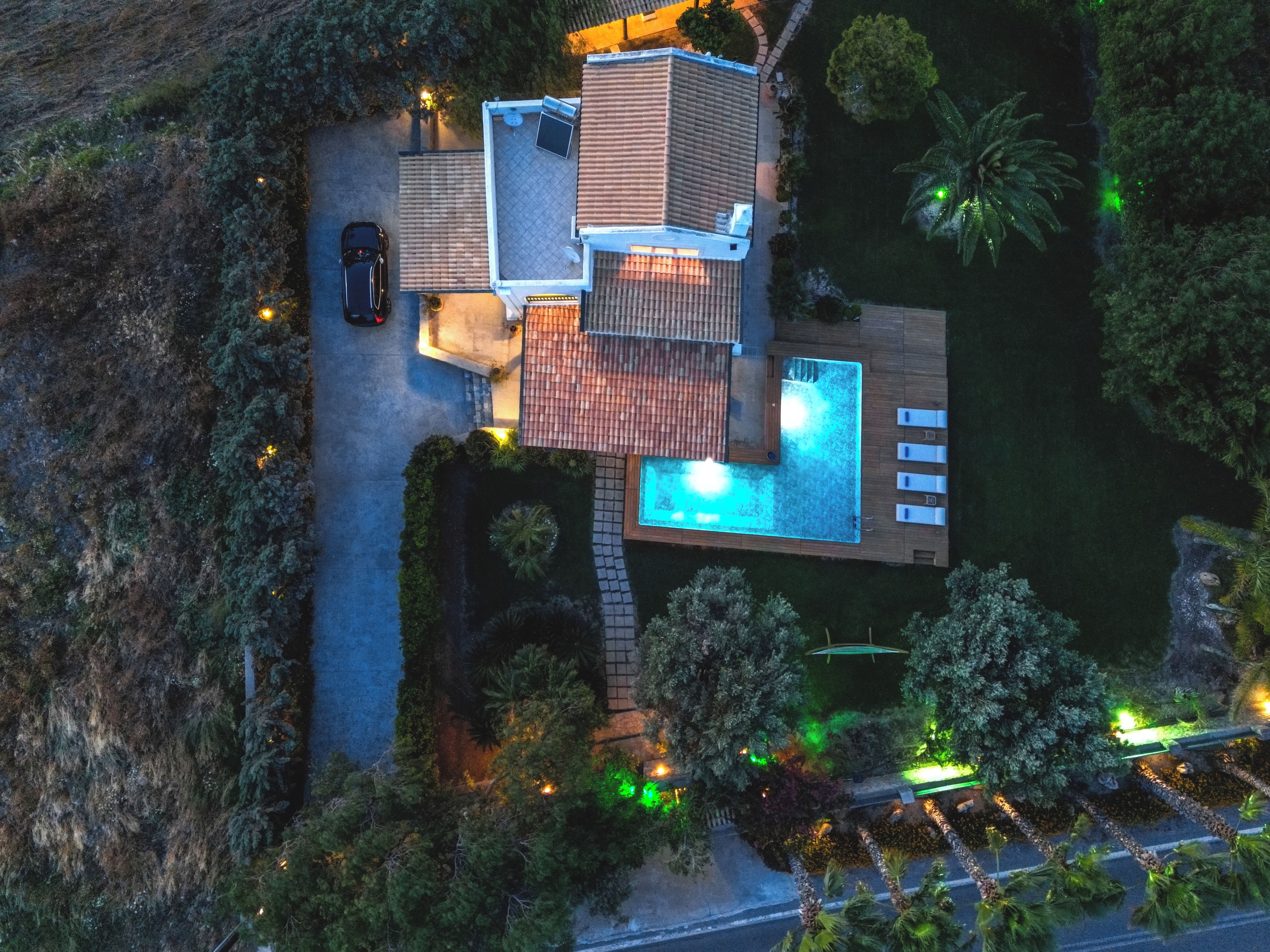 Propiedad residencial con piscina, patio cubierto y un automóvil estacionado afuera.