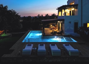 Une piscine avec des chaises longues et un espace patio aménagé avec du mobilier d’extérieur.
