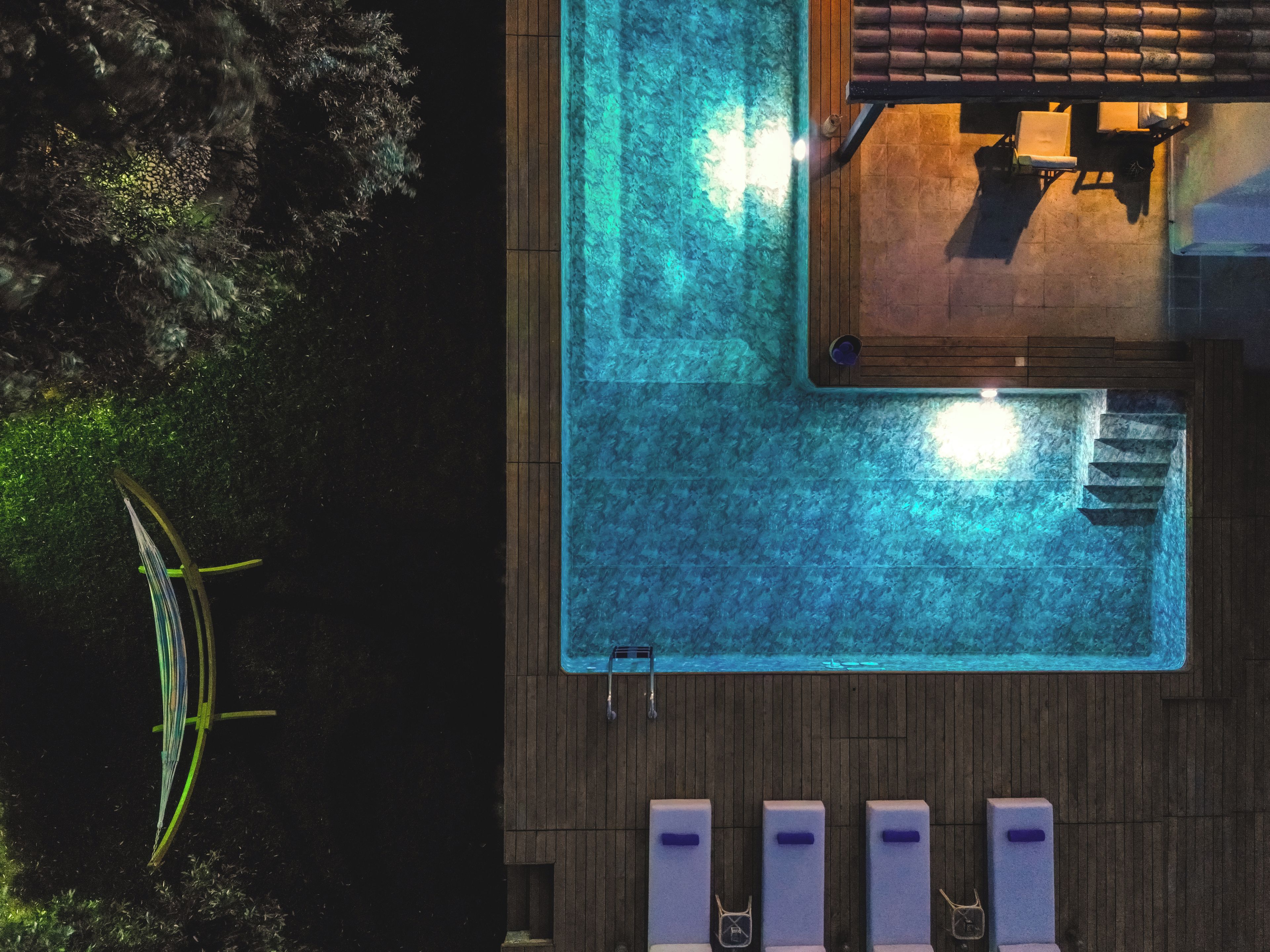 Ein Dachpool mit Holzterrasse, Liegestühlen und einem kleinen Tisch.