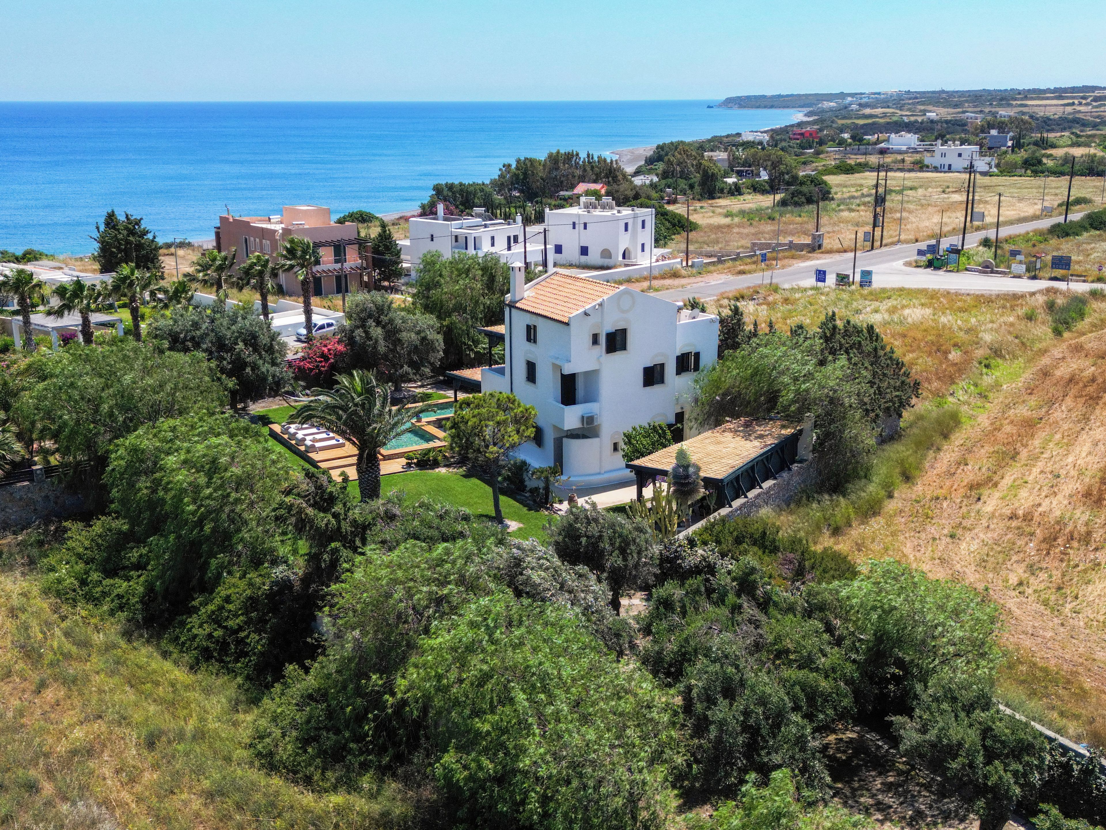Una propiedad costera con piscina, varias construcciones y vista al mar.