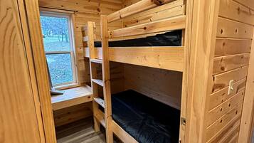 A wooden bunk bed room with a window, a shelf, and a door.