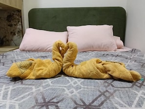 A bed with a patterned bedspread, two pillows, and a pair of yellow slippers. - Khoufu Garden (Giza)