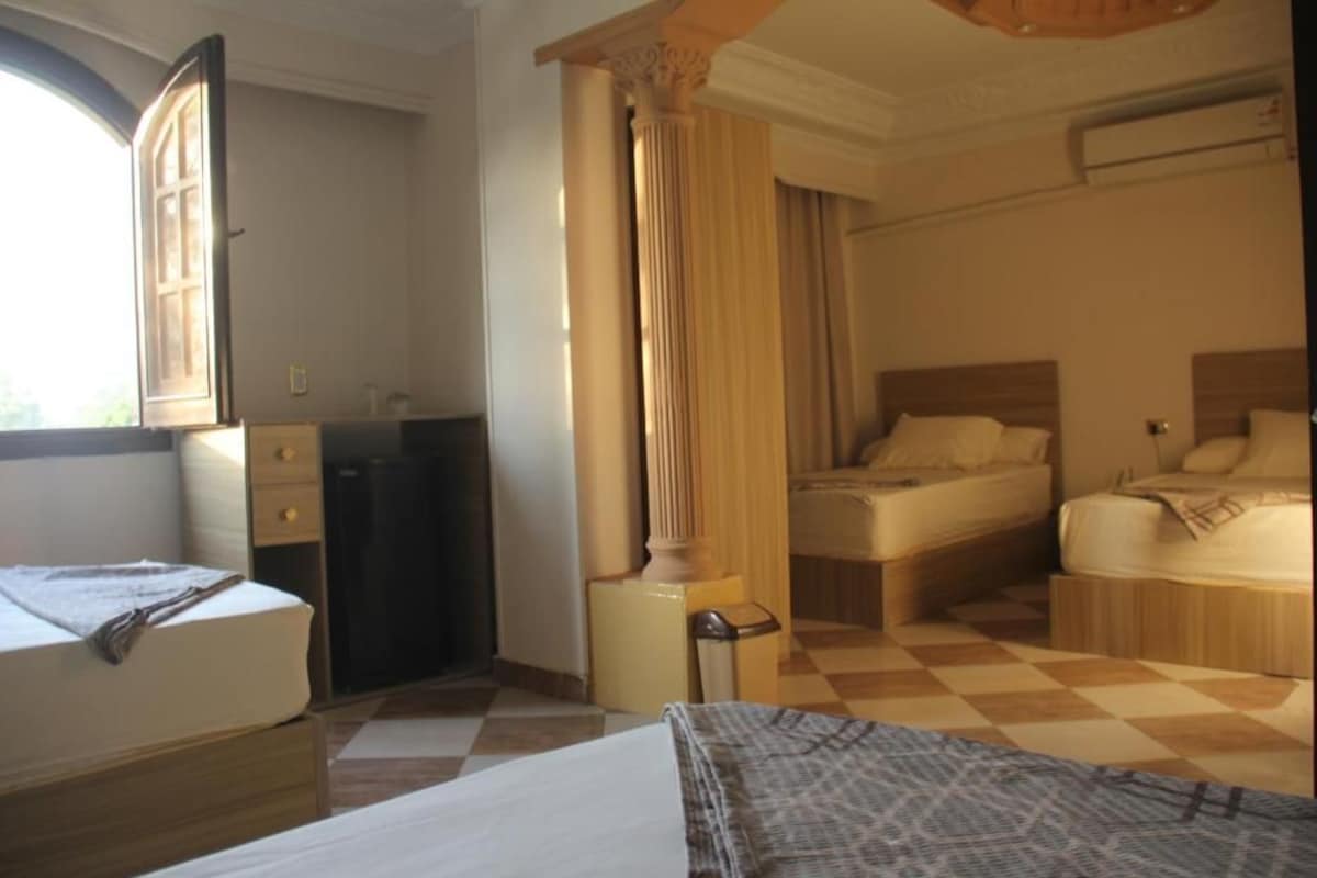 A hotel room with a bed, a desk, a chair, a wardrobe, and a window.