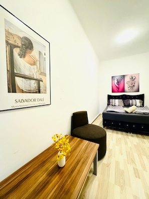 Una habitación moderna con una mesa de madera, un banco, un sofá y dos obras de arte en la pared.