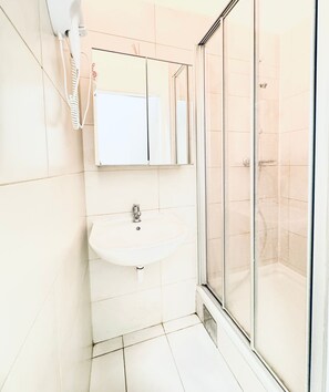 Une salle de bain avec un lavabo blanc, un miroir et une cabine de douche en verre.