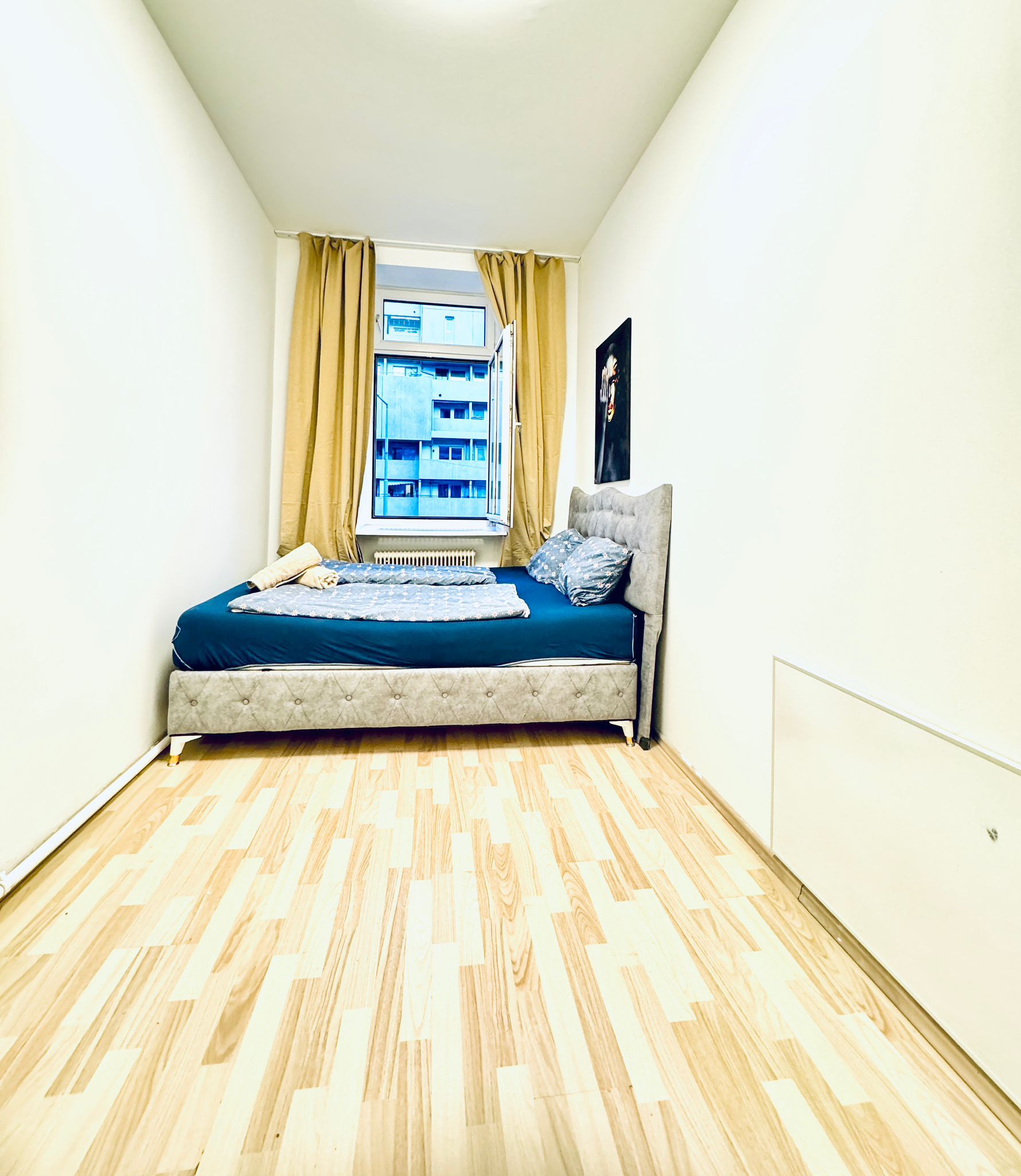 Un dormitorio con una cama, una ventana con cortinas y un radiador.
