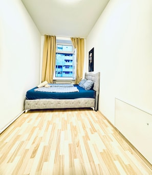 Un dormitorio con una cama, una ventana con cortinas y un radiador.