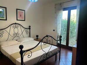 A bed with a metal frame, a bedside table with a lamp, and a window with curtains.