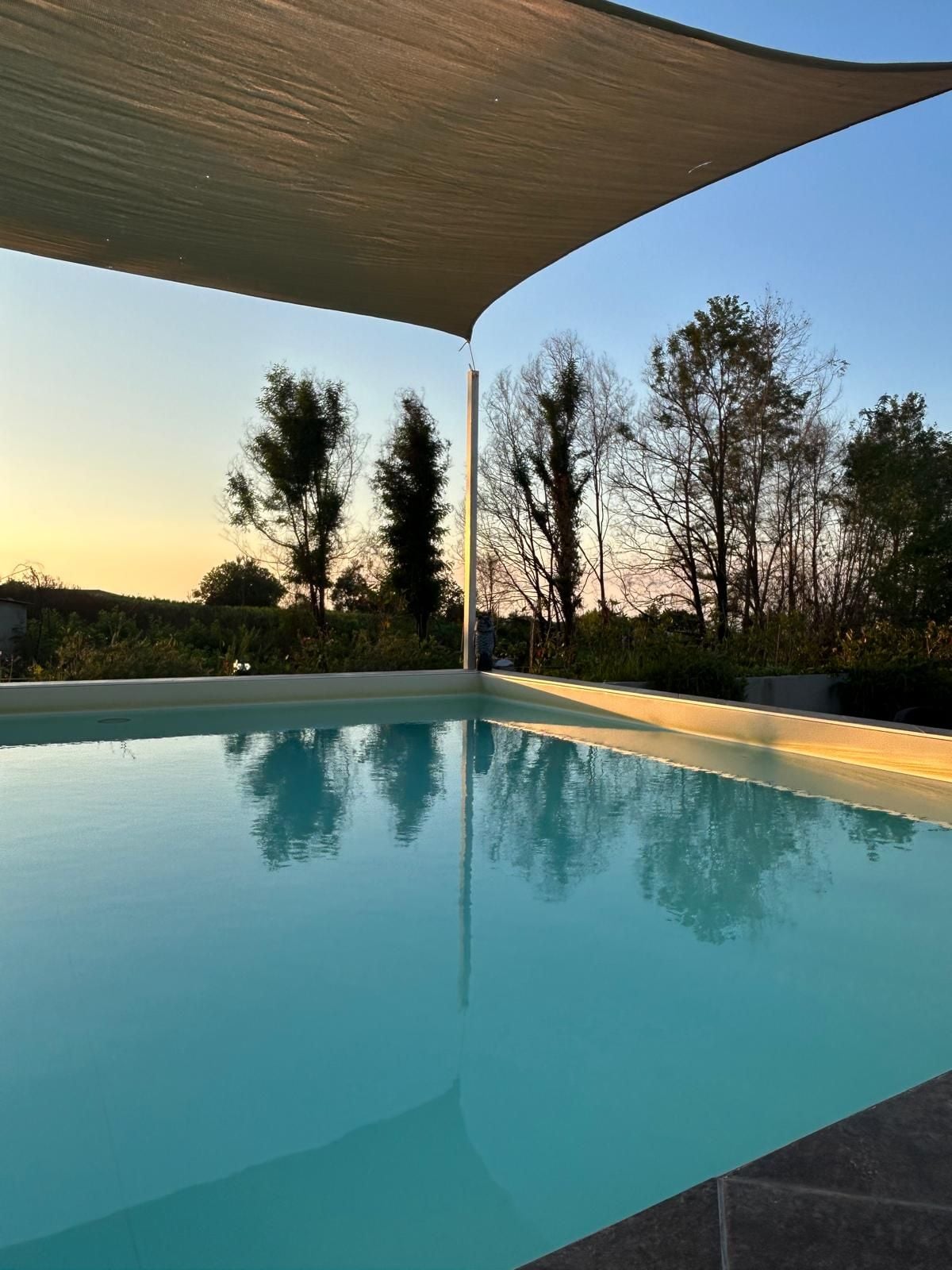 Une piscine offrant une vue dégagée sur les arbres et un coucher de soleil en arrière-plan.