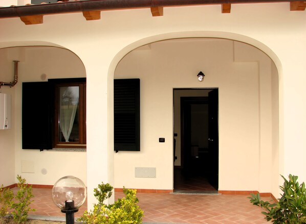 A building with a tiled entrance, a door, and a window with a curtain.