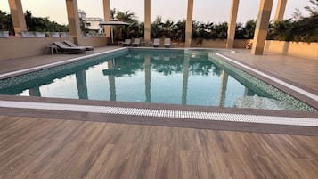 A swimming pool with lounge chairs and a wooden deck.