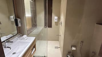 A modern bathroom with a glass-enclosed shower, a white sink, and a toilet.