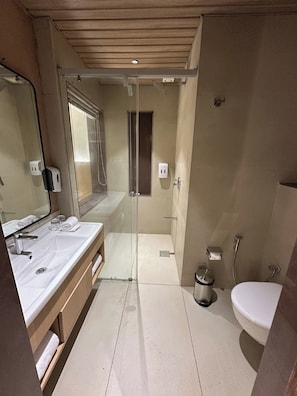 A modern bathroom with a glass-enclosed shower, a white sink, and a toilet. - Imperia by The Sky Imperial Somnath (Keshod)