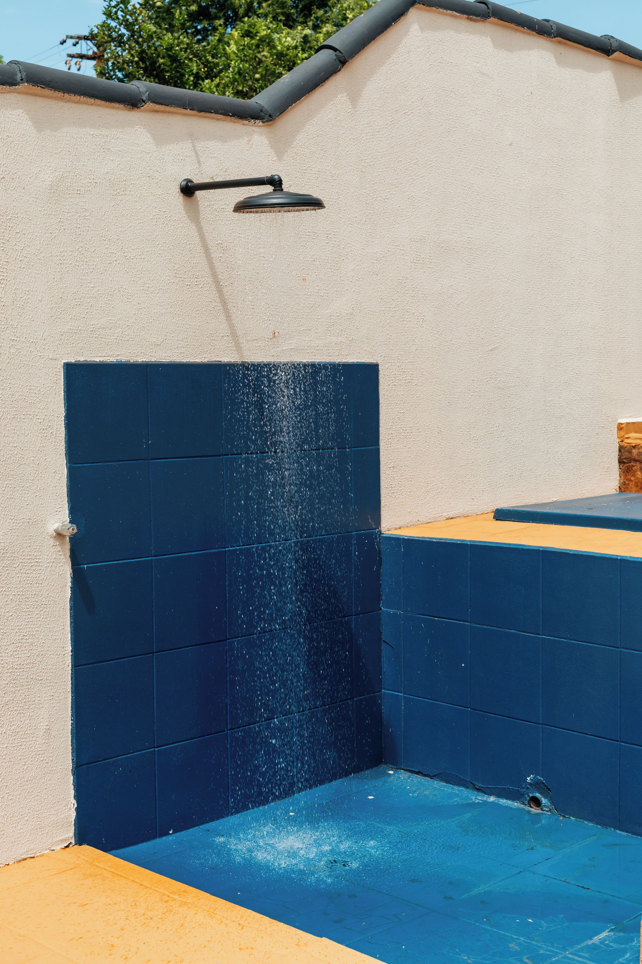 Une piscine avec un mur recouvert de carreaux bleus et une gouttière noire au-dessus.
