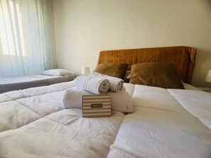Et hotelværelse med en pænt redt seng, en pude, et sammenrullet håndklæde og et skilt, der angiver en minibar.