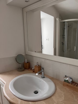Un bagno con un lavandino bianco, uno specchio e una cabina doccia in vetro.