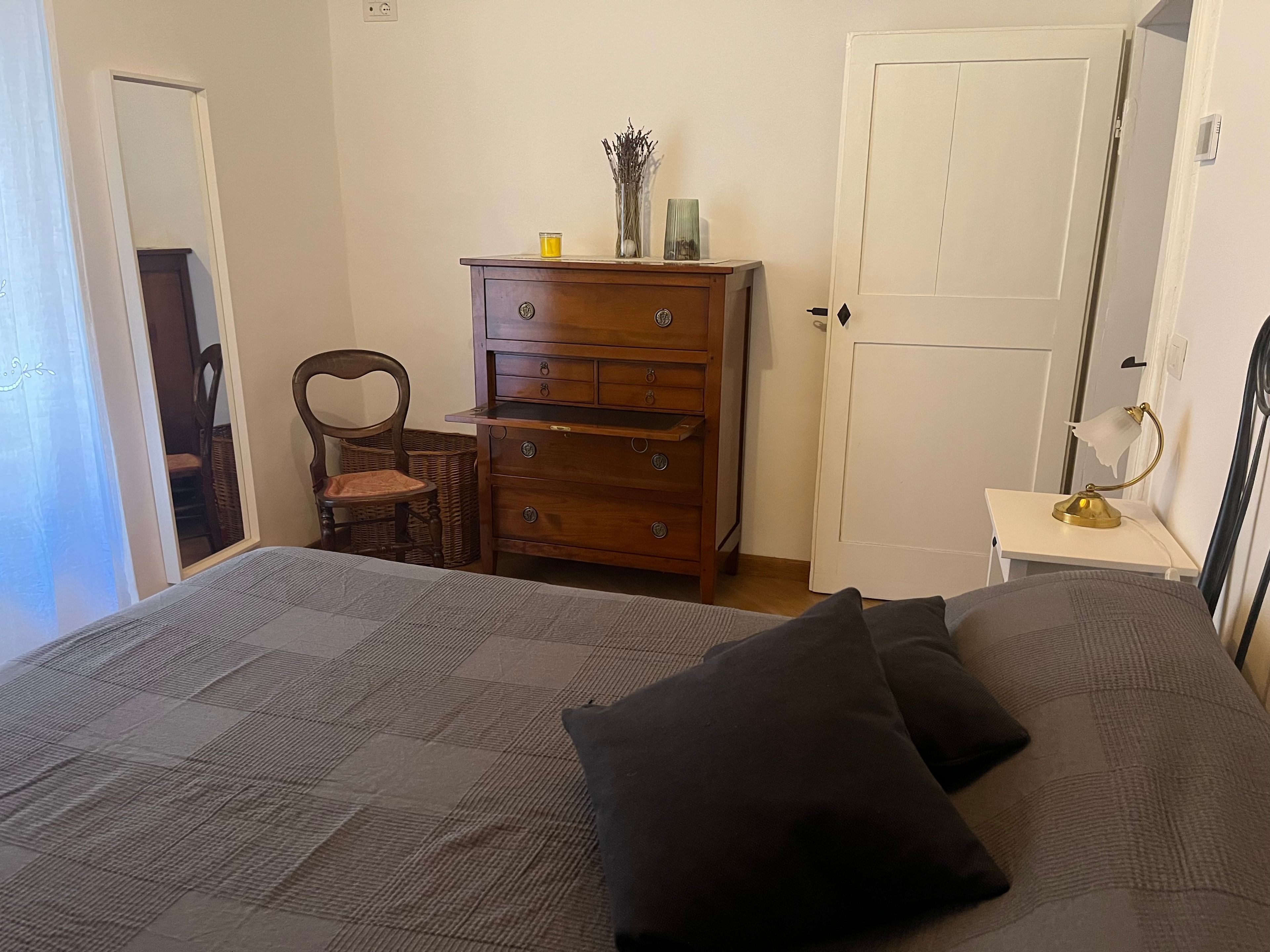 Ein Schlafzimmer mit einem Bett, einem Schminktisch, einem Stuhl und einer Tür.