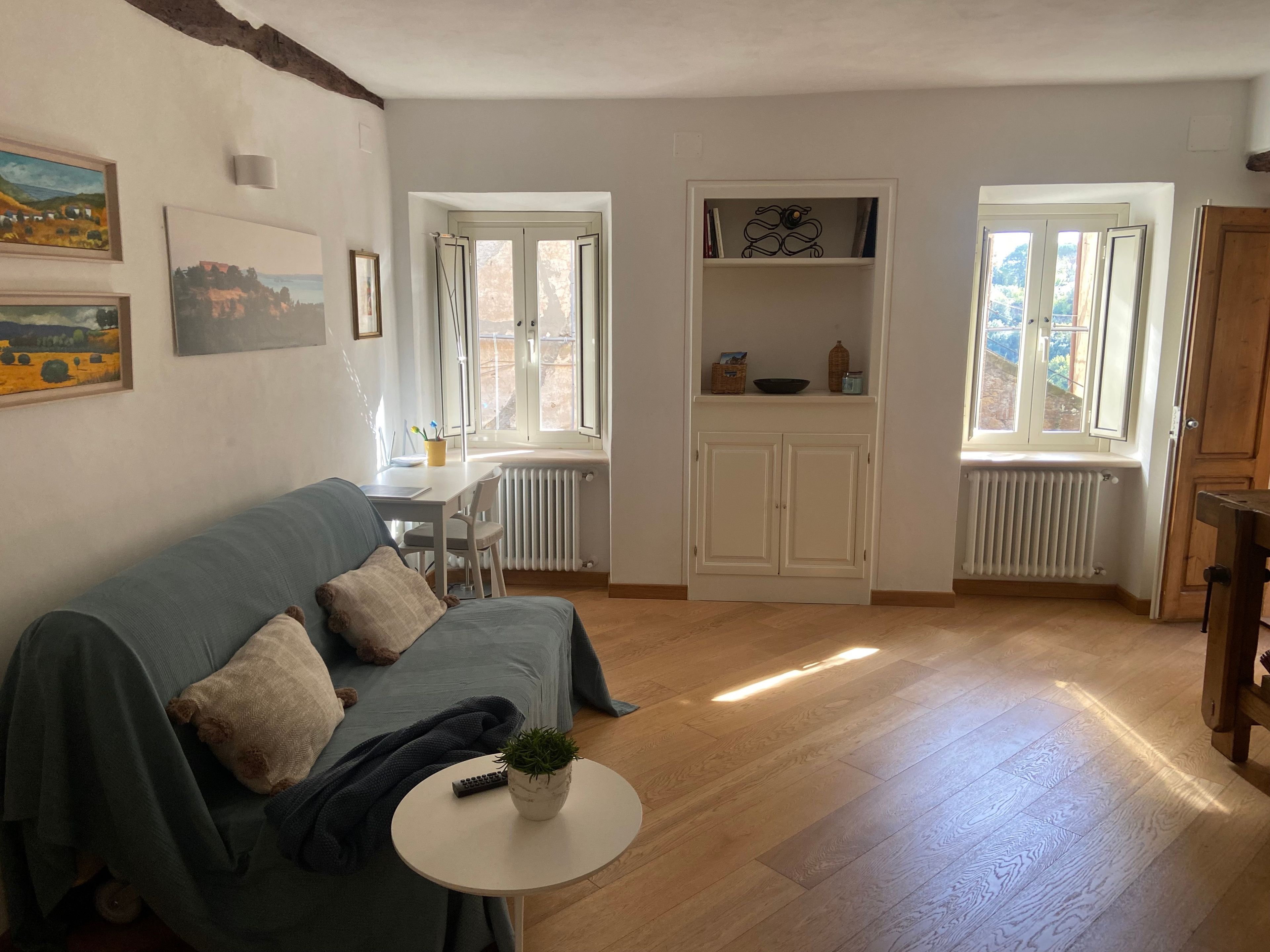 Ein Wohnzimmer mit einer Couch, einem kleinen runden Tisch mit einer Pflanze und einem Essbereich mit Tisch und Stühlen.