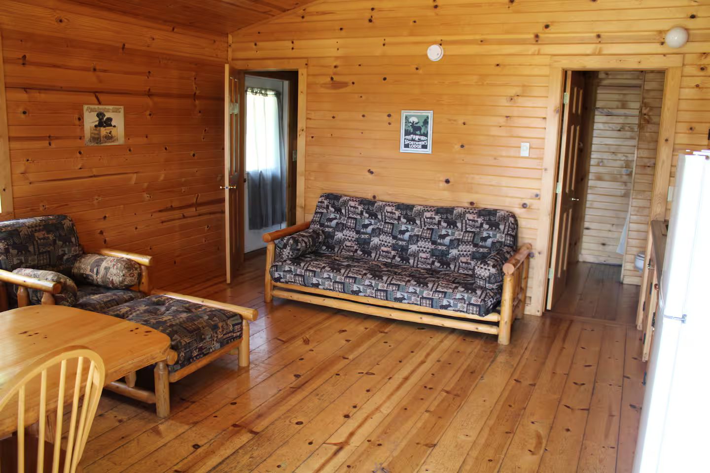 A wooden interior with a sofa, chairs, and a table.