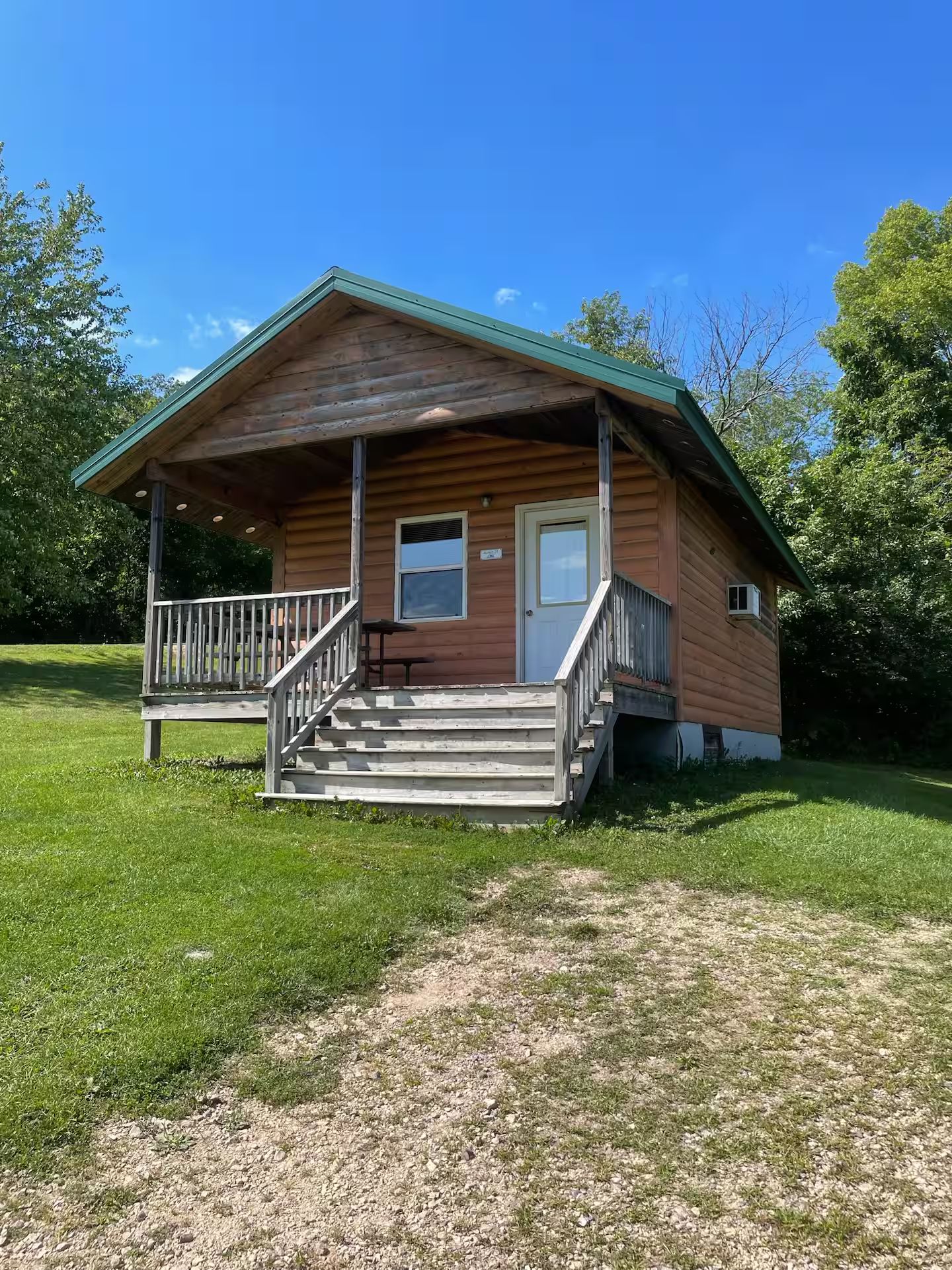 A wooden cabin with a porch, a front door, and a small window.