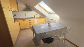 Et lille køkken med ovenlys, et spisebord med stole og en lille ø.