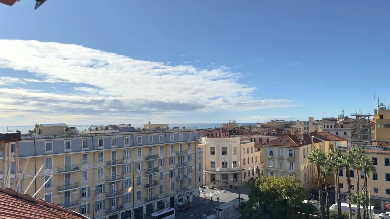 En bygning med flere etager og altaner, en klar himmel og havudsigt i det fjerne.