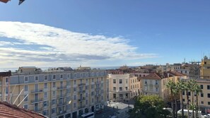 En bygning med flere etager og altaner, en klar himmel og havudsigt i det fjerne.