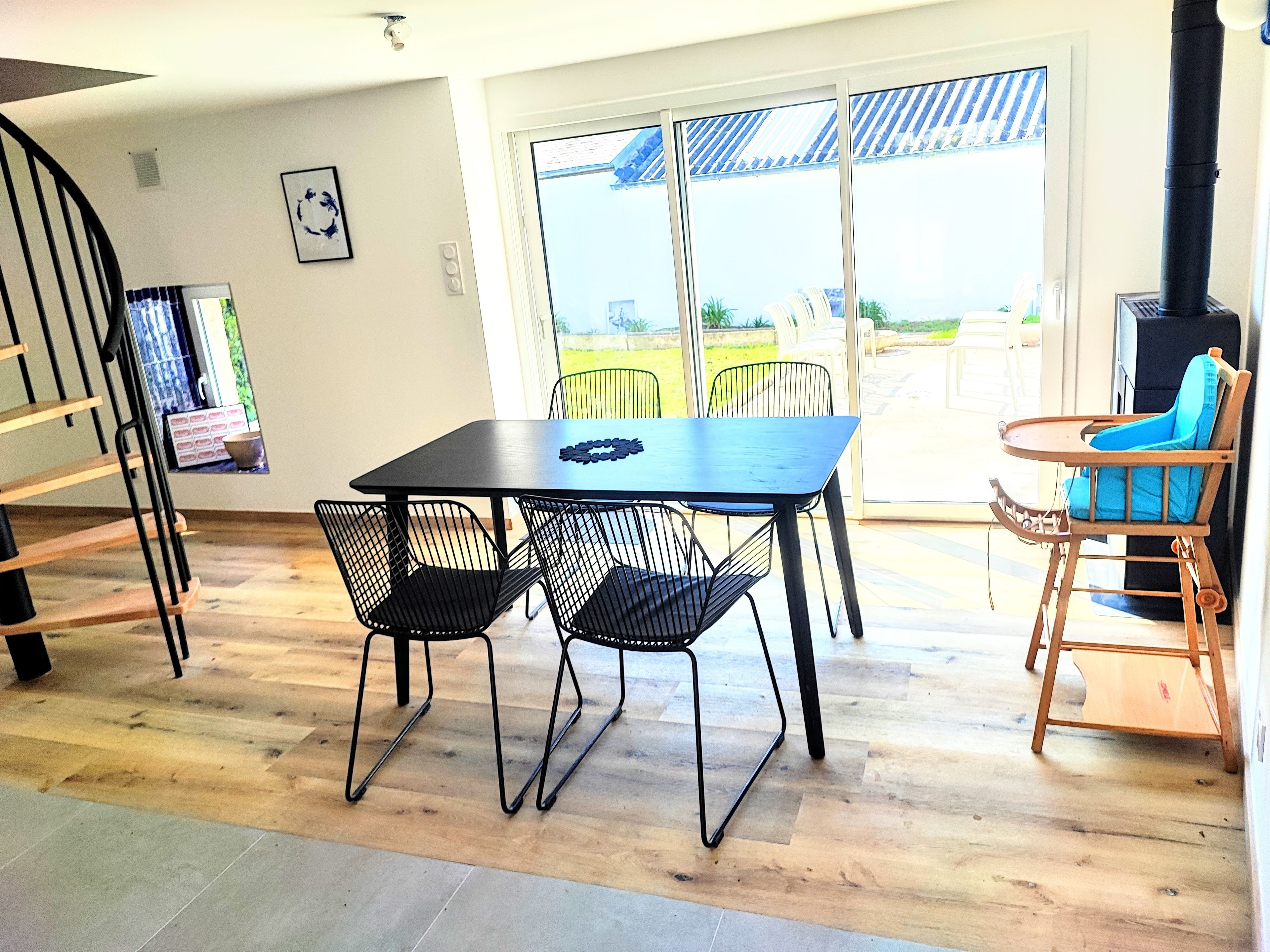 Un coin repas avec une table et des chaises, un escalier et une vue à travers une porte vitrée.