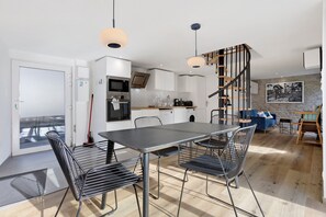 A modern kitchen with a dining area, a staircase, and a view of the outside.