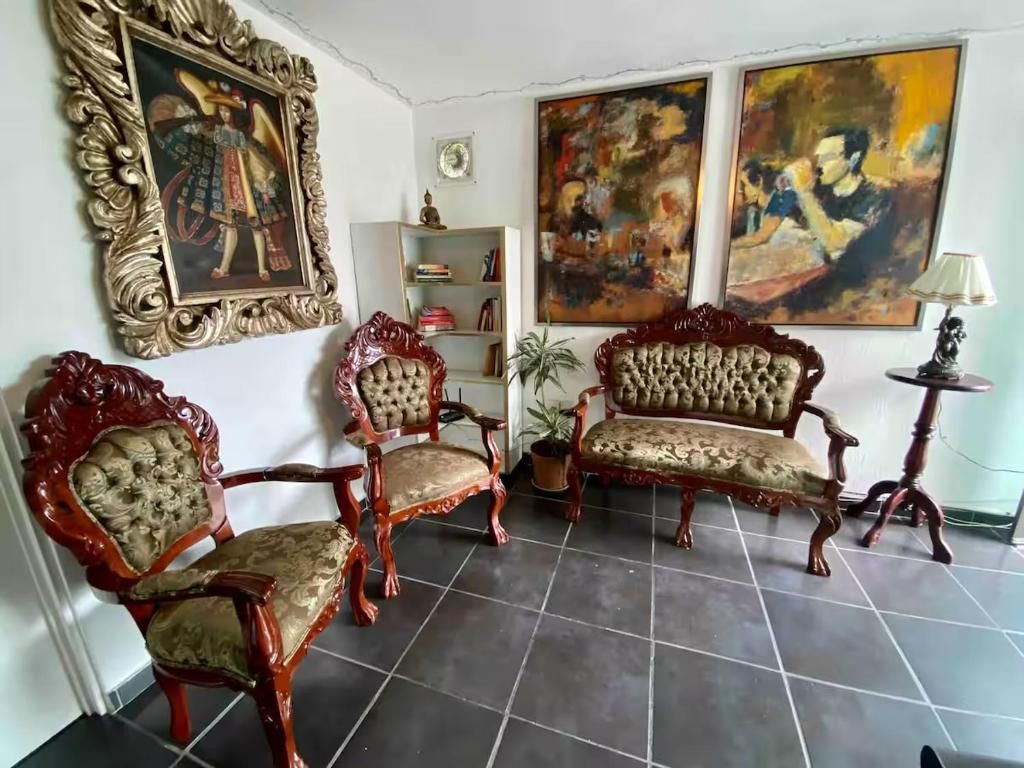 Una habitación con un sofá, dos sillones, una mesita y una planta en maceta.