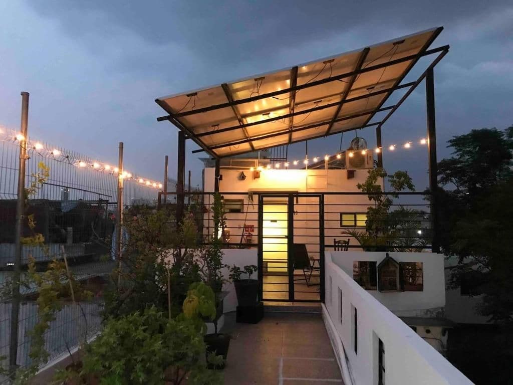 Un espacio al aire libre cubierto con una puerta, plantas en macetas y una guirnalda de luces.