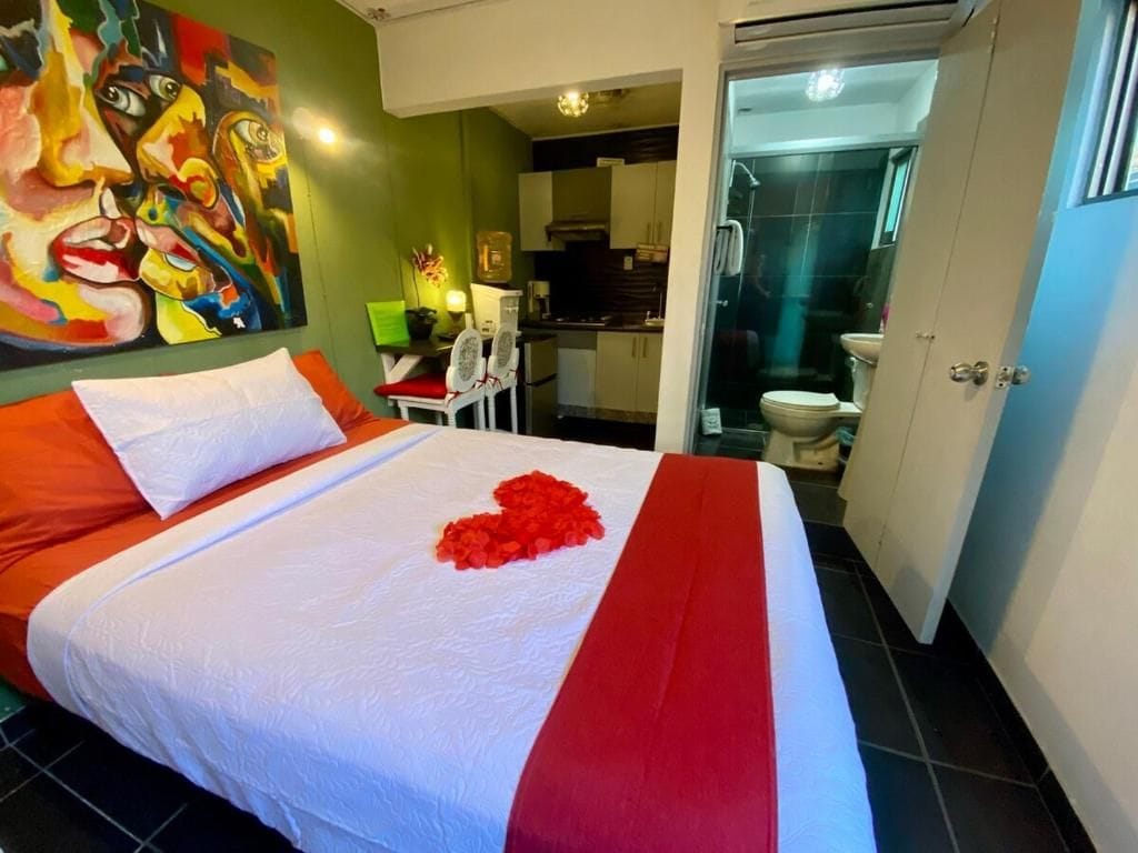Habitación de hotel con cama, un cuadro en la pared y vista al baño.