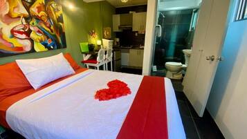 Habitación de hotel con cama, un cuadro en la pared y vista al baño.