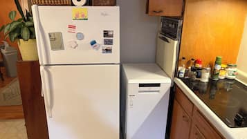 Eine Küche mit Kühlschrank, Mikrowelle und einer Arbeitsfläche mit verschiedenen Lebensmitteln.