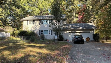 A two-story house with a garage, surrounded by trees and a driveway.