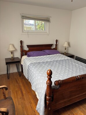 A bedroom with a wooden bed, two bedside tables with lamps, a window with blinds, and a chair. - Clean large space in Upscale Stow. Near KSU, Akron U, Akron and Cuyahoga Valley. (Stow)