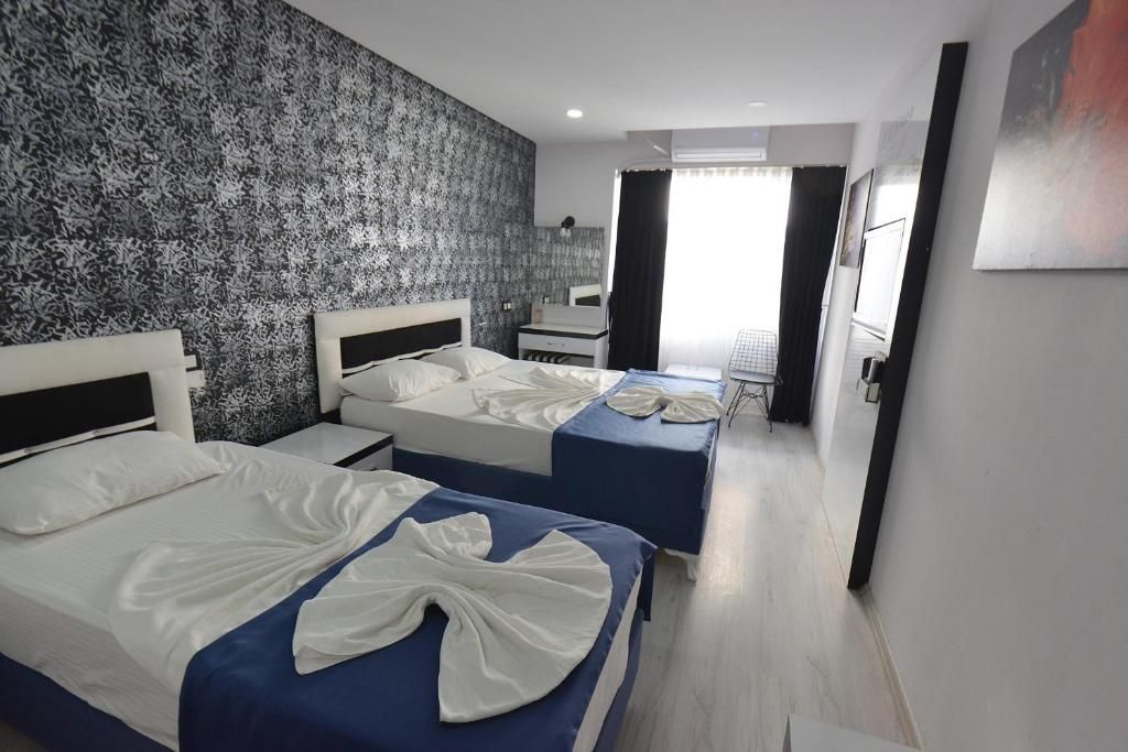 Habitación de hotel con dos camas, un escritorio, una silla y un espejo.