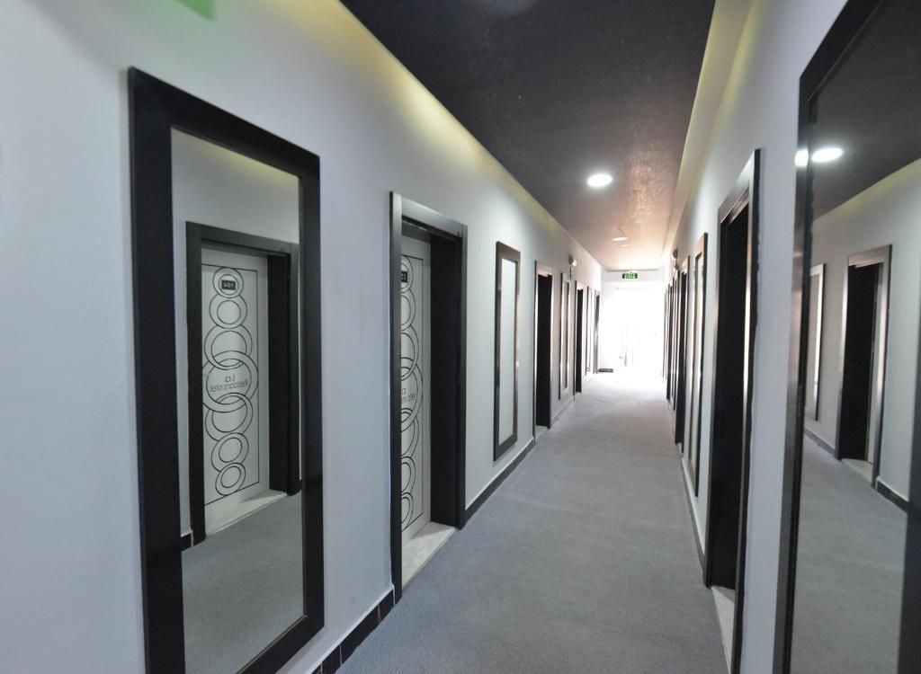 Un pasillo largo y estrecho con puertas a ambos lados, que da acceso a habitaciones individuales.