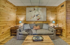 A cozy room with a wooden interior, a sofa, two lamps, and a painting on the wall. - Laurel Lodge on Fightingtown Creek (Blue Ridge,)