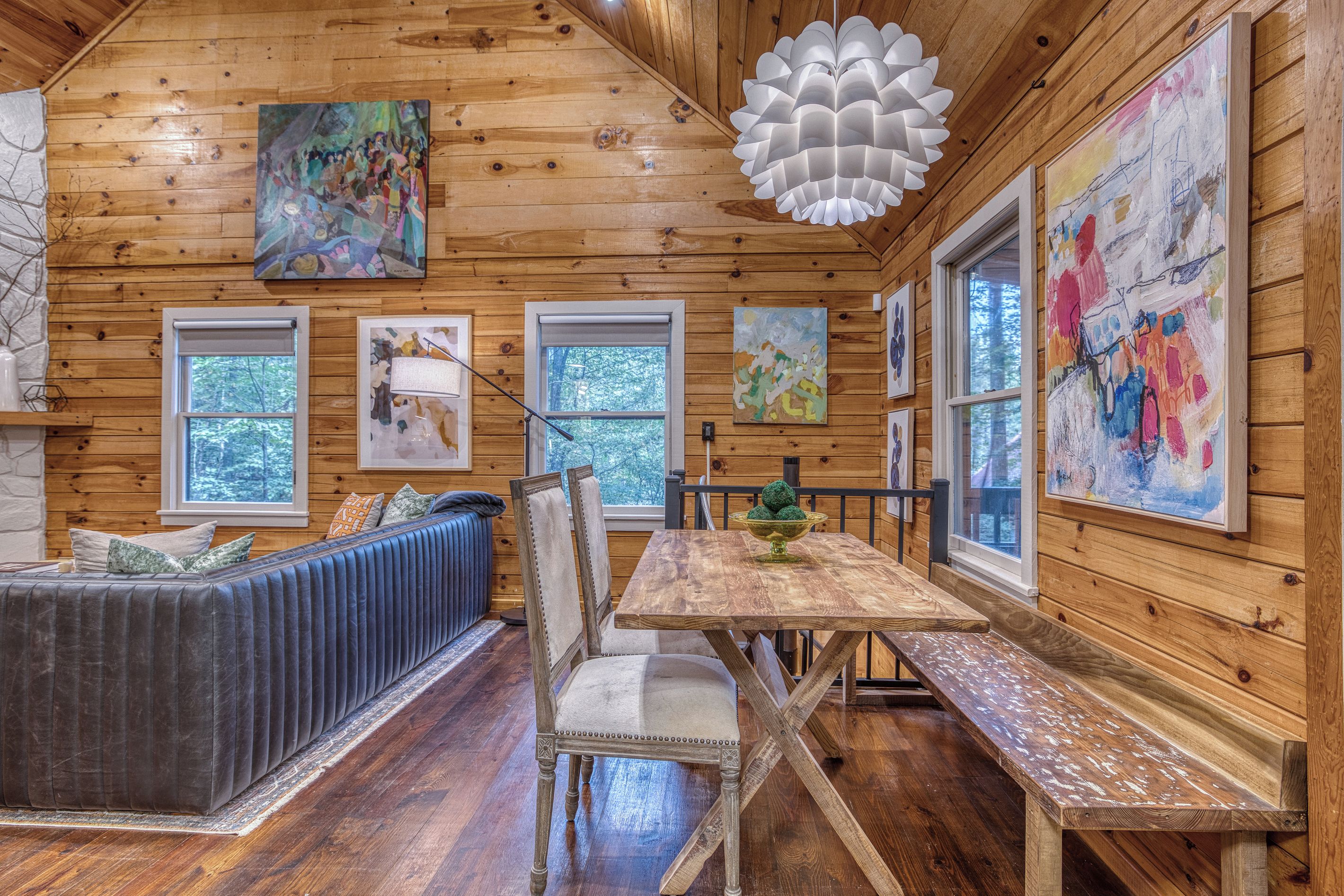 L'interno accogliente di una baita, con arredamento in legno, un tavolo da pranzo, una panca e opere d'arte alle pareti.