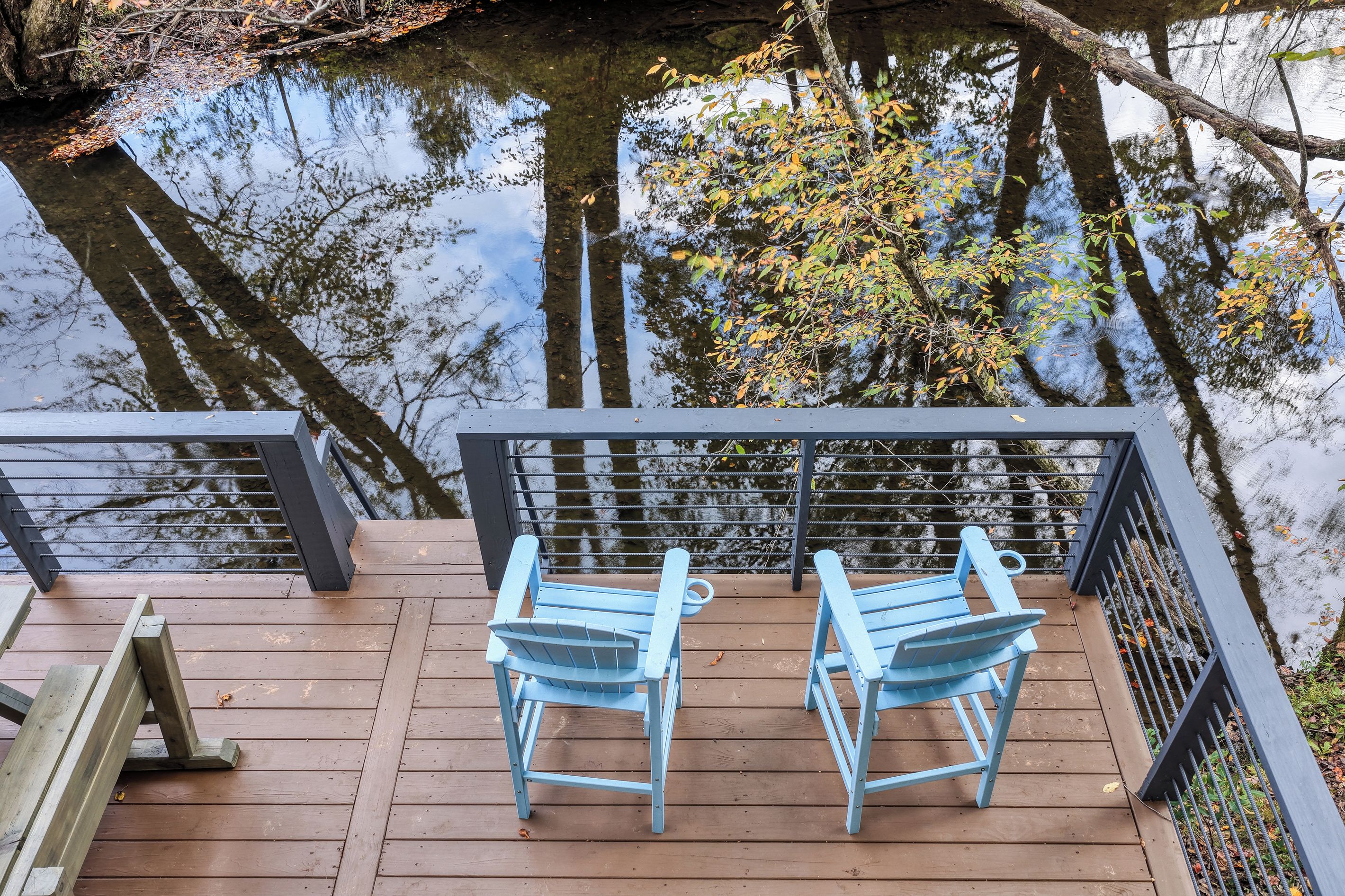 Un pontile in legno con due sedie blu e una ringhiera che si affaccia su una distesa d'acqua.