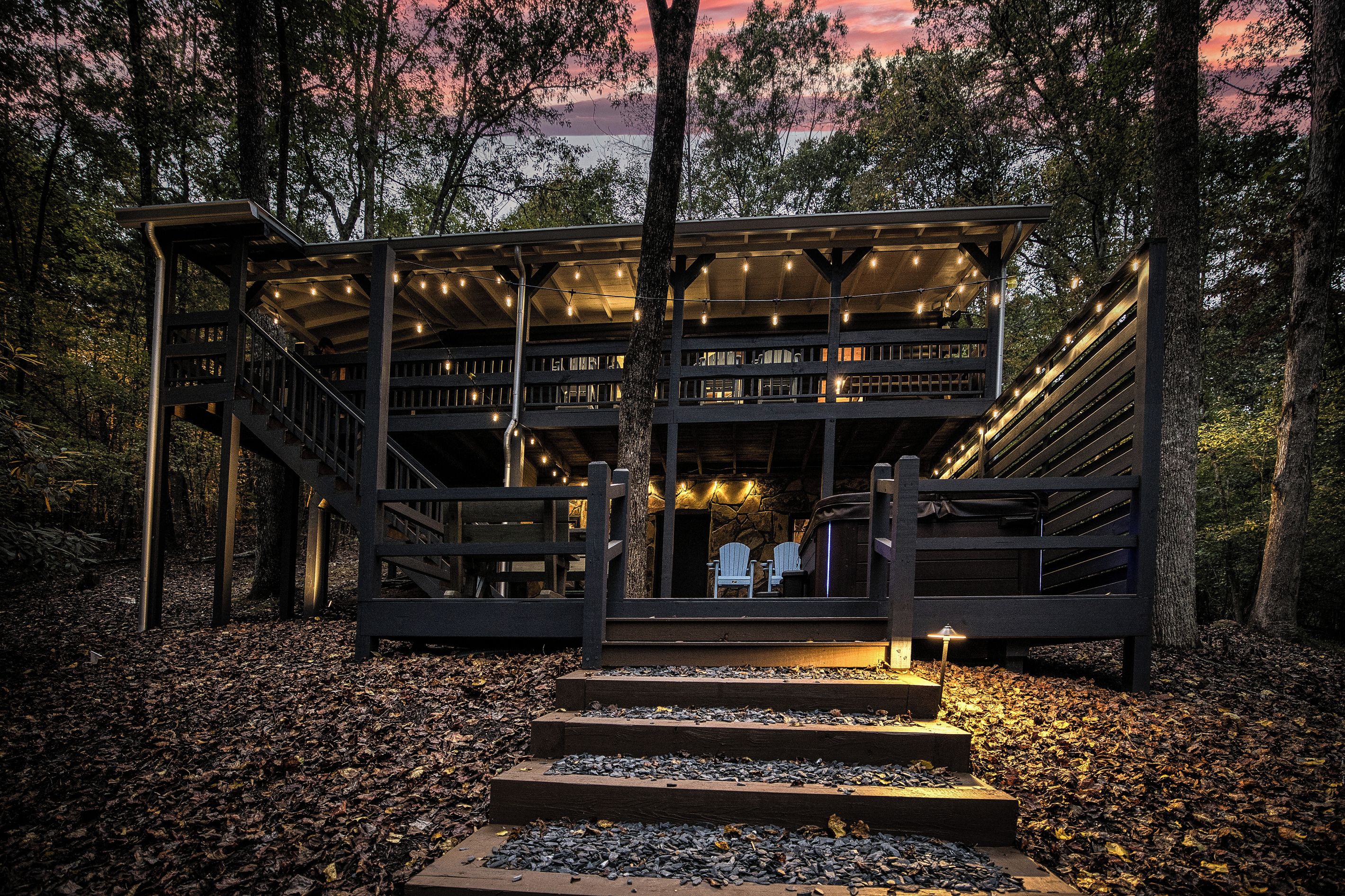 A multi-level wooden structure with outdoor seating and a staircase leading up to it.