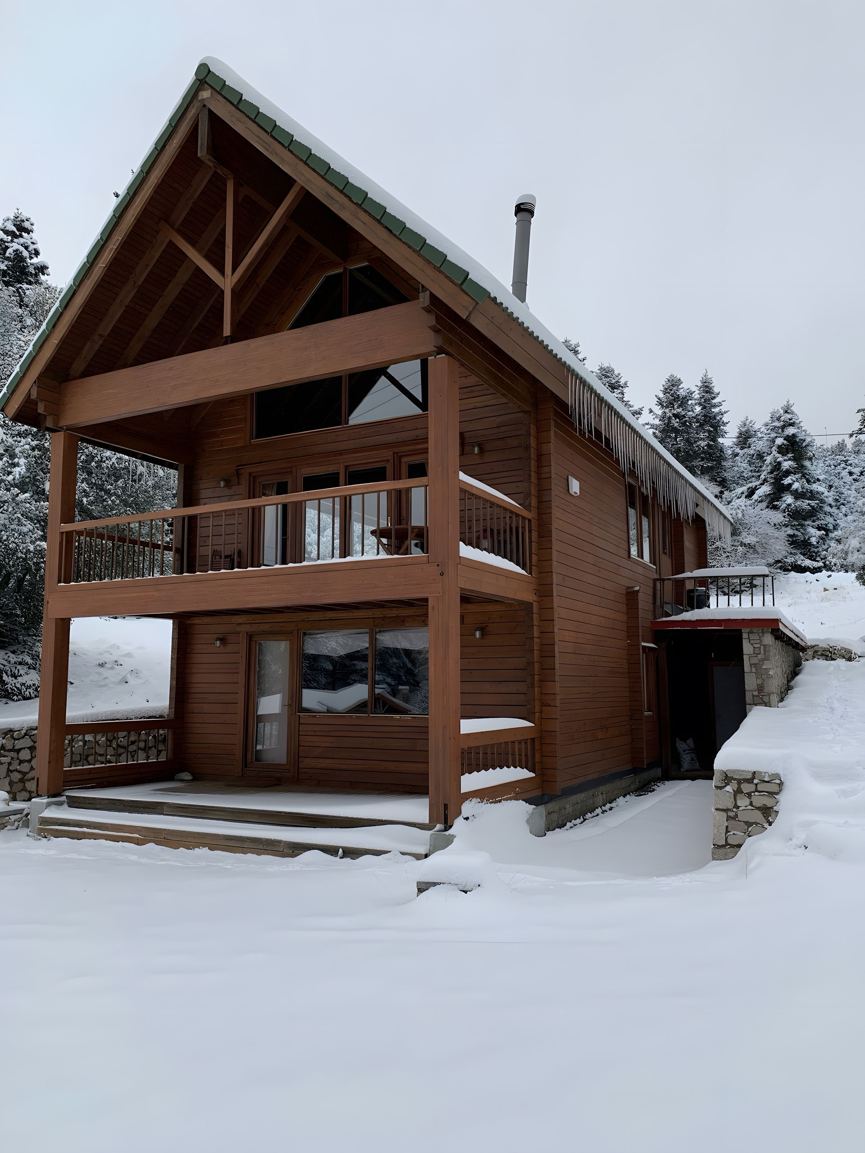 Eine zweistöckige Holzhütte mit Balkon, Schornstein und Steinunterbau.