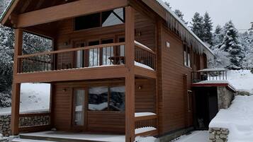 Eine zweistöckige Holzhütte mit Balkon, Schornstein und Steinunterbau.