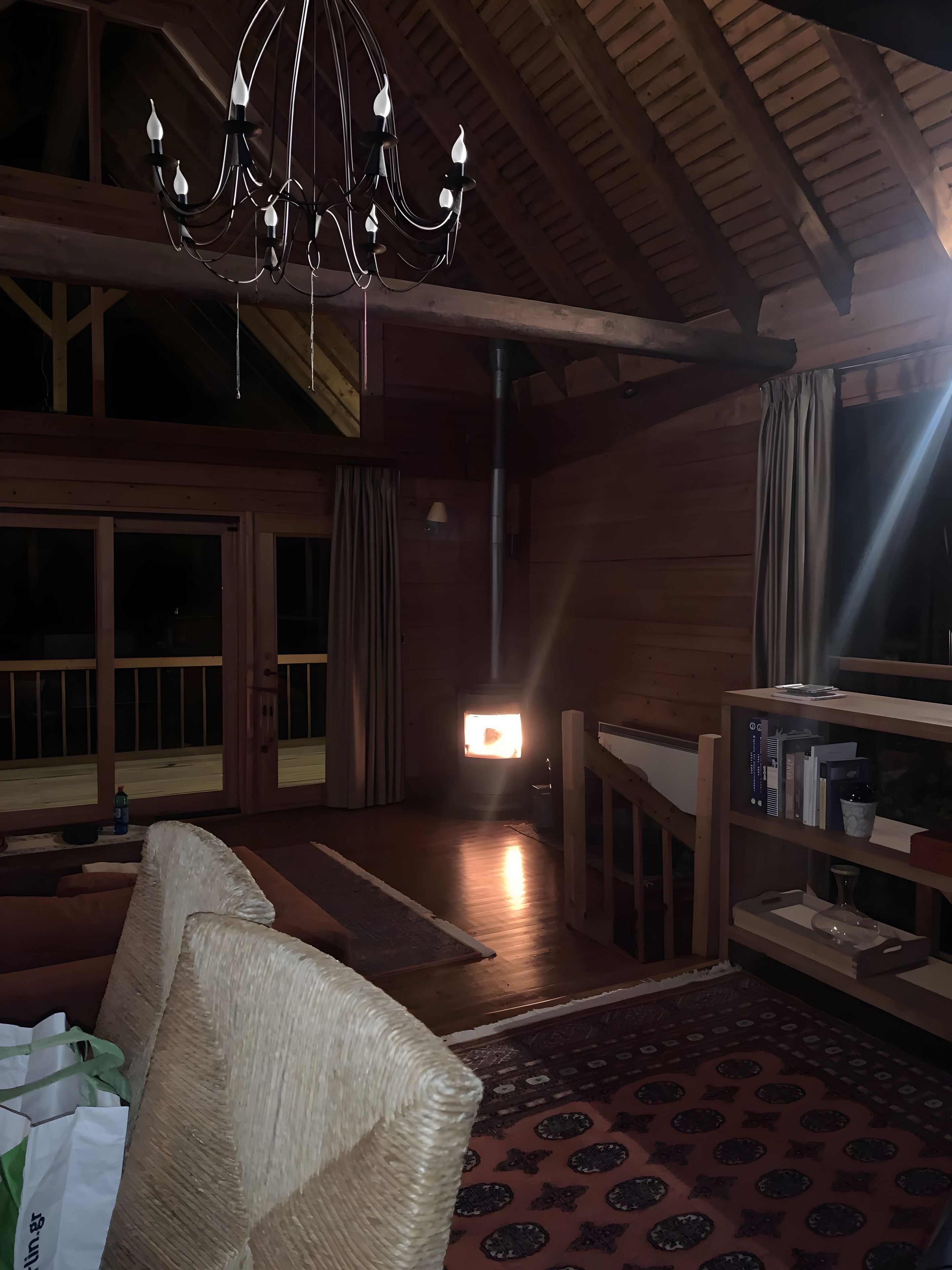 Une pièce chaleureuse avec un plafond en bois, un lustre, une cheminée et une bibliothèque.